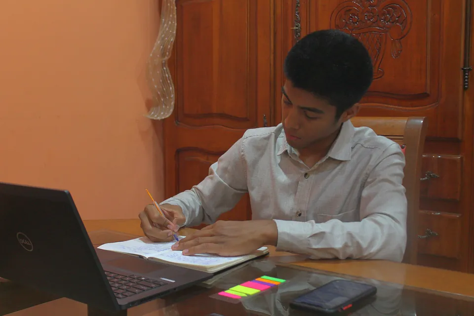 Joaquín Caballero escribiendo en su cuaderno junto a la computadora